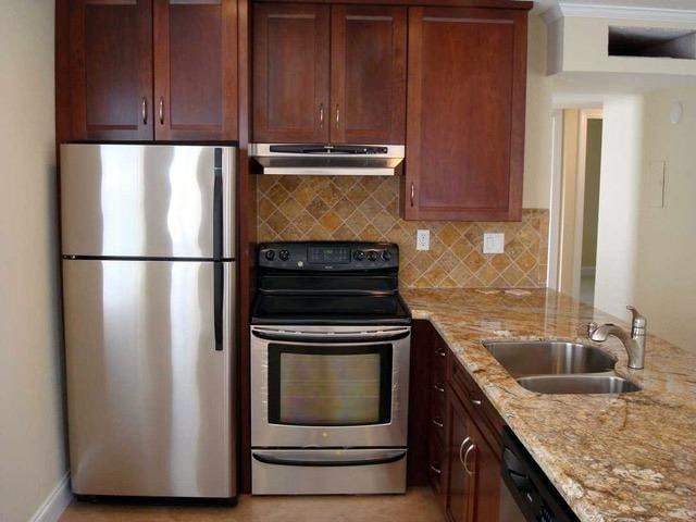 kitchen featuring light stone countertops, appliances with stainless steel finishes, sink, and tasteful backsplash