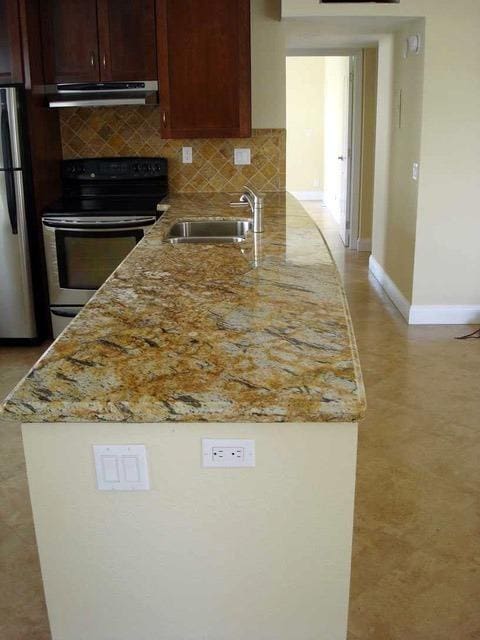 kitchen with stainless steel fridge, sink, black electric range, backsplash, and light stone countertops