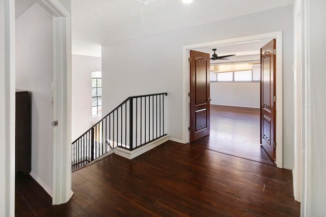 hall with a textured ceiling and dark wood-type flooring