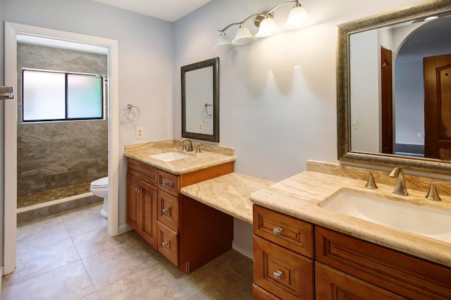 bathroom with dual bowl vanity, tile patterned floors, a tile shower, and toilet