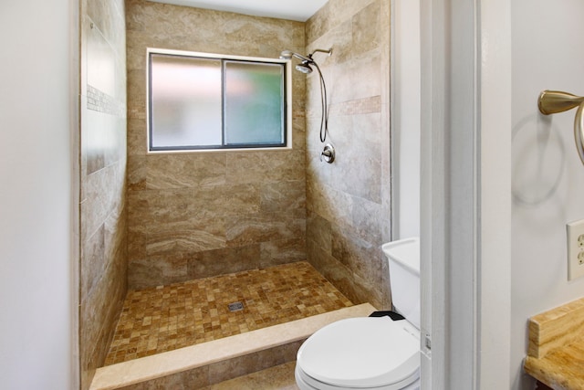 bathroom featuring tiled shower and toilet