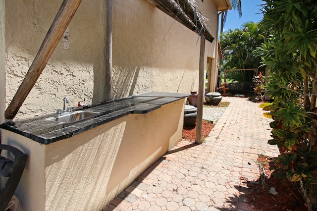 view of side of property with area for grilling, a patio area, and sink