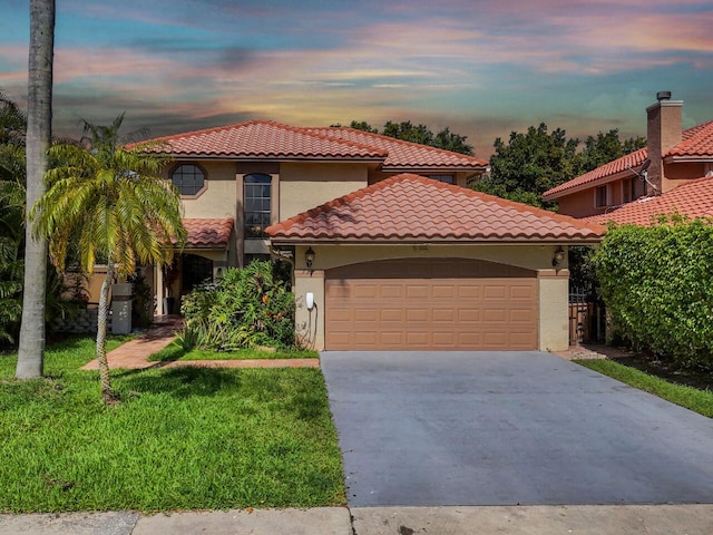 mediterranean / spanish house with a garage and a lawn