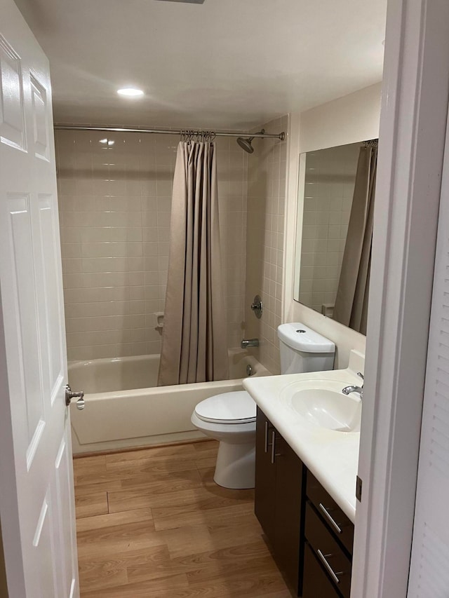 full bathroom featuring vanity, toilet, hardwood / wood-style flooring, and shower / bathtub combination with curtain