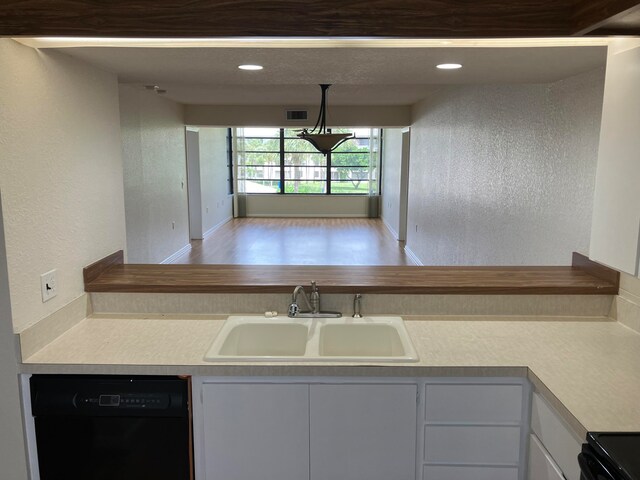 kitchen with wood-type flooring, black dishwasher, white cabinetry, and sink