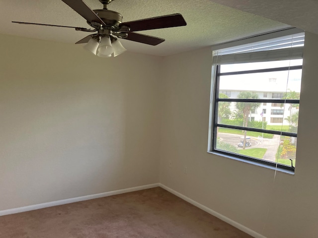 empty room with ceiling fan, carpet, and a textured ceiling