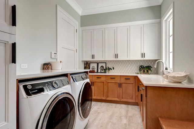 laundry area featuring washing machine and clothes dryer, light hardwood / wood-style flooring, ornamental molding, and plenty of natural light