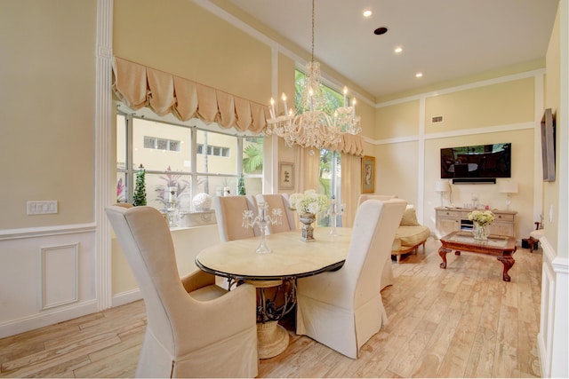 dining space with a notable chandelier, light hardwood / wood-style floors, and a towering ceiling