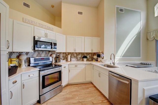 kitchen featuring light hardwood / wood-style floors, white cabinetry, tasteful backsplash, and stainless steel appliances