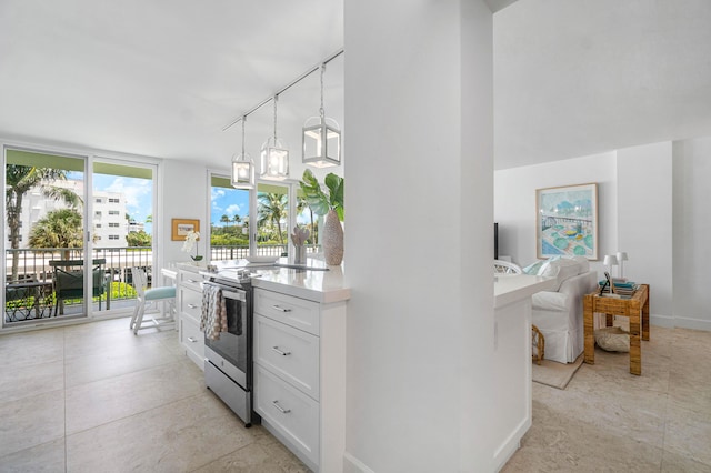 kitchen with white cabinetry, rail lighting, hanging light fixtures, expansive windows, and stainless steel electric range