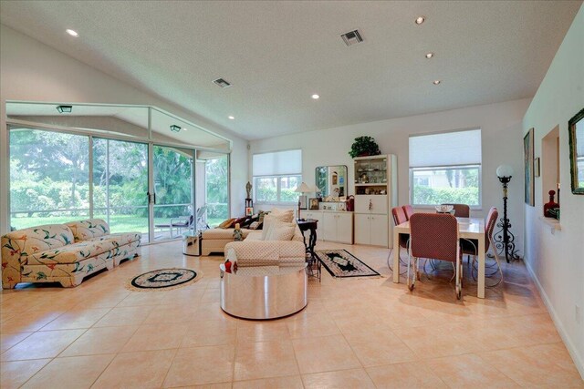 tiled living room with a healthy amount of sunlight, vaulted ceiling, and a textured ceiling