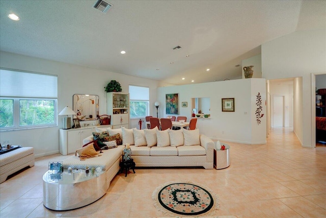 living room with a textured ceiling, light tile patterned floors, and vaulted ceiling