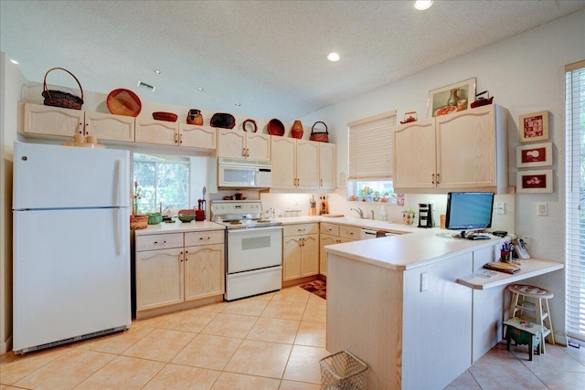 kitchen featuring white appliances, light brown cabinets, kitchen peninsula, light tile patterned floors, and a textured ceiling