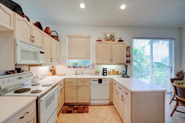 kitchen with light tile patterned flooring, light brown cabinets, white appliances, sink, and a textured ceiling