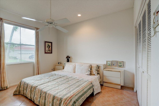 tiled bedroom featuring a textured ceiling, a closet, lofted ceiling, and ceiling fan