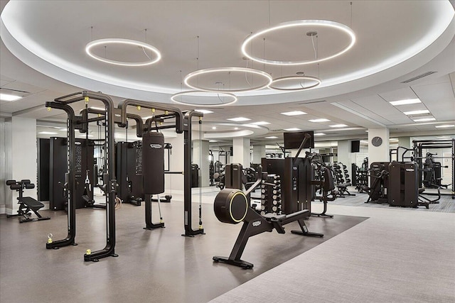 exercise room with a paneled ceiling and a tray ceiling