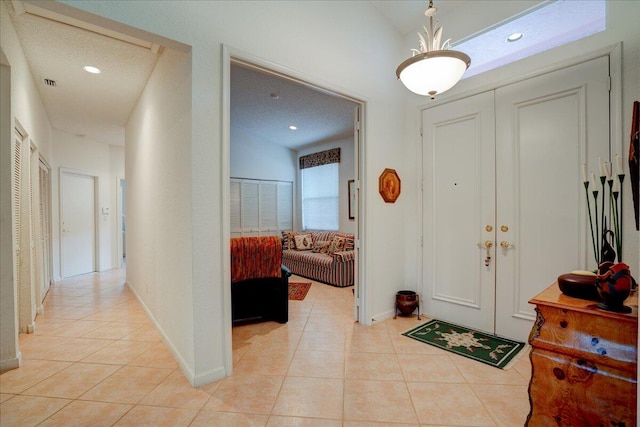 entryway with a textured ceiling, light tile patterned floors, and lofted ceiling