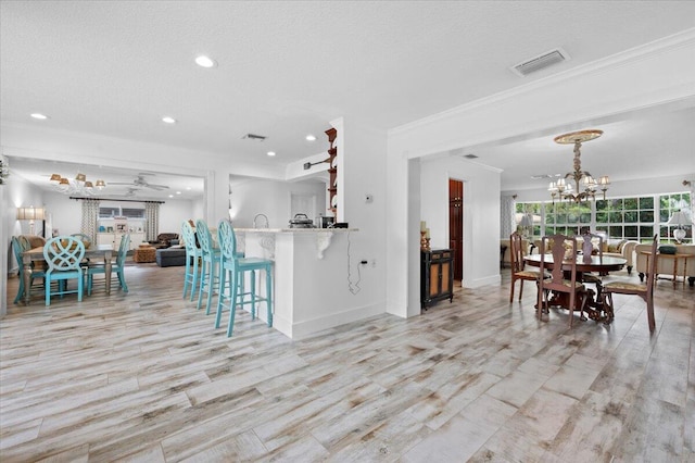 dining room with a textured ceiling, ceiling fan with notable chandelier, and light wood-type flooring