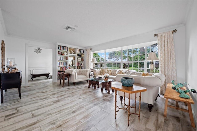 living room with built in shelves, light wood-type flooring, and ornamental molding