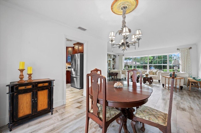 dining area with light hardwood / wood-style floors and a notable chandelier