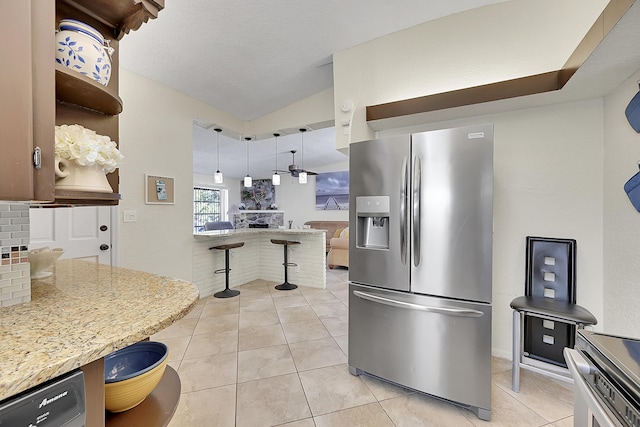 kitchen featuring light tile patterned floors, stainless steel fridge, tasteful backsplash, lofted ceiling, and pendant lighting