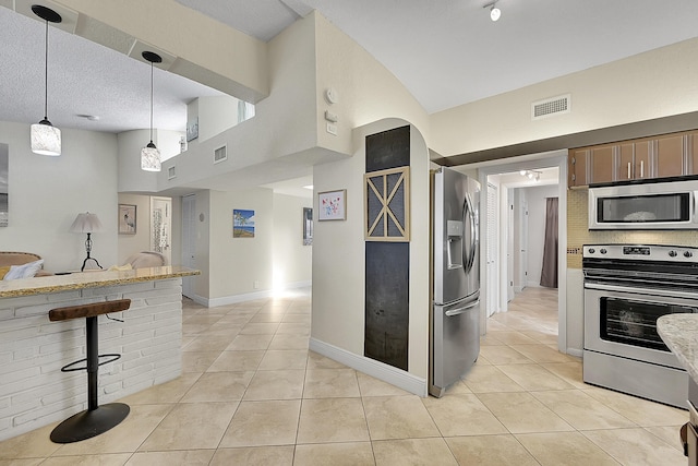 kitchen featuring a breakfast bar, light tile patterned floors, stainless steel appliances, and decorative backsplash