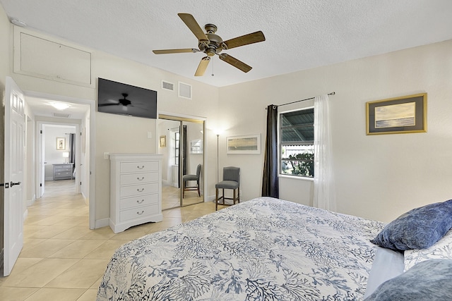 bedroom with a ceiling fan, visible vents, a textured ceiling, and light tile patterned flooring