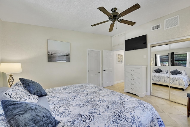 bedroom with a closet, visible vents, a textured ceiling, and light tile patterned floors