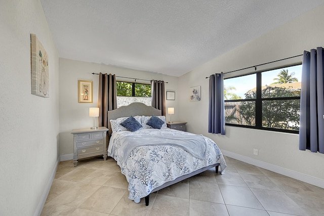 bedroom featuring a textured ceiling, light tile patterned floors, and baseboards