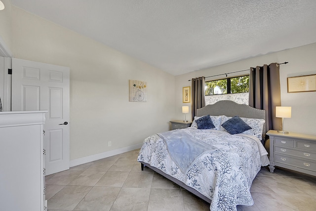 bedroom featuring lofted ceiling, baseboards, a textured ceiling, and light tile patterned flooring