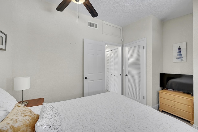 bedroom featuring a closet, visible vents, a textured wall, ceiling fan, and a textured ceiling