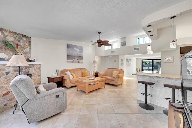 tiled living room with a textured ceiling, ceiling fan, and a high ceiling