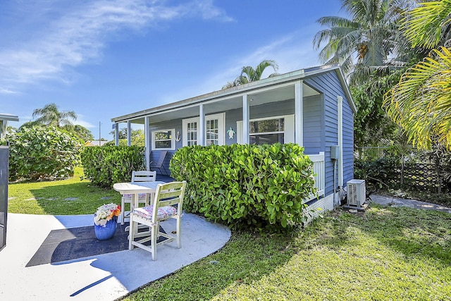 view of front of home featuring a patio, a front yard, and central air condition unit