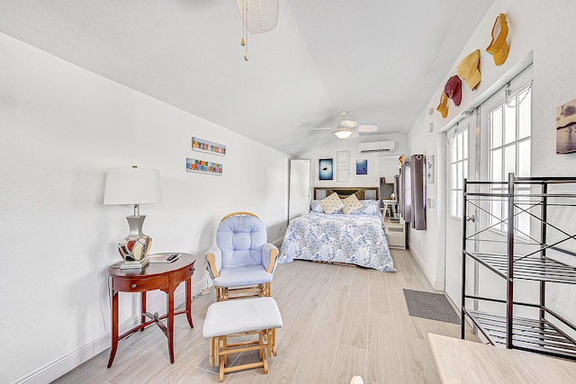 bedroom featuring a ceiling fan, vaulted ceiling, light wood-type flooring, a wall mounted air conditioner, and baseboards