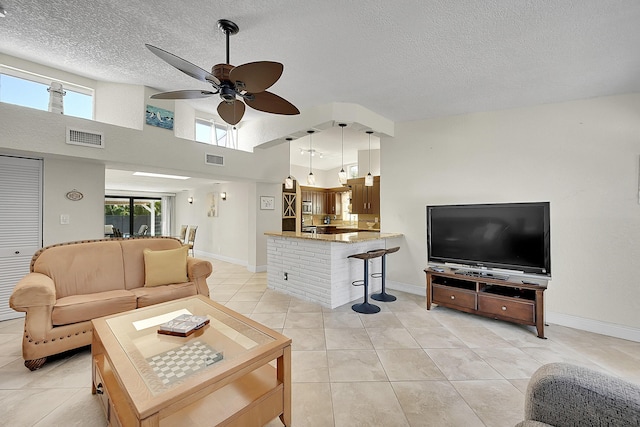 living area with a textured ceiling, visible vents, a ceiling fan, and light tile patterned flooring