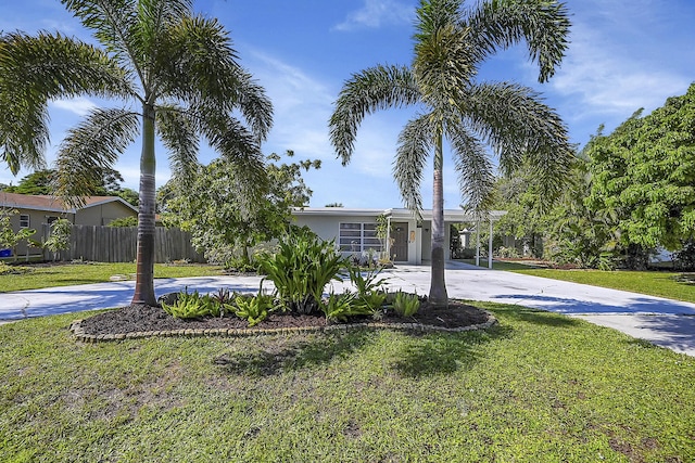 view of front facade with driveway, fence, and a front lawn