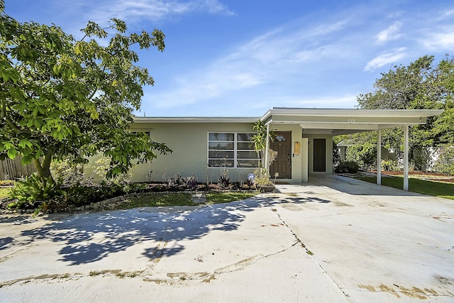 view of front facade with driveway, fence, a carport, and stucco siding