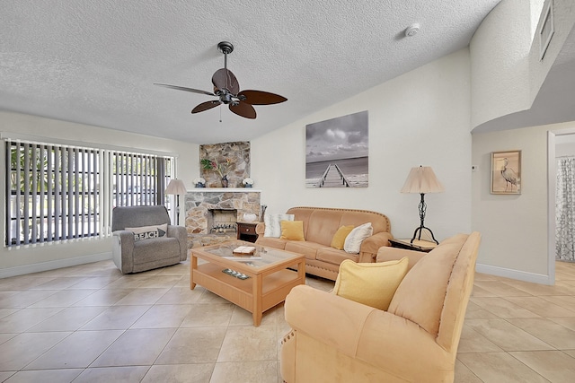 living room with a ceiling fan, light tile patterned flooring, vaulted ceiling, a stone fireplace, and a textured ceiling