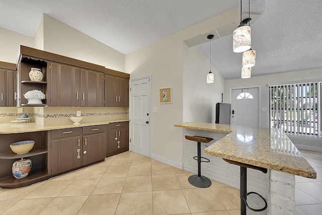 kitchen with a breakfast bar area, open shelves, backsplash, vaulted ceiling, and a peninsula