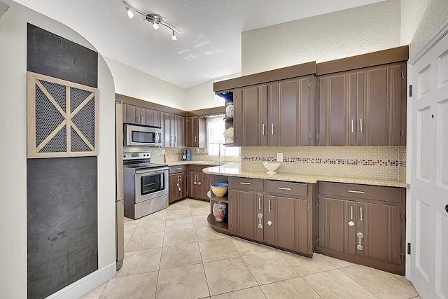 kitchen with light tile patterned floors, dark brown cabinetry, stainless steel appliances, backsplash, and open shelves