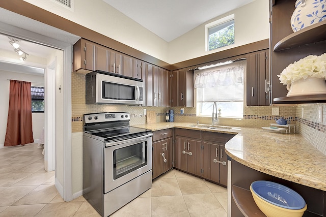 kitchen featuring appliances with stainless steel finishes, tasteful backsplash, a sink, and light tile patterned floors