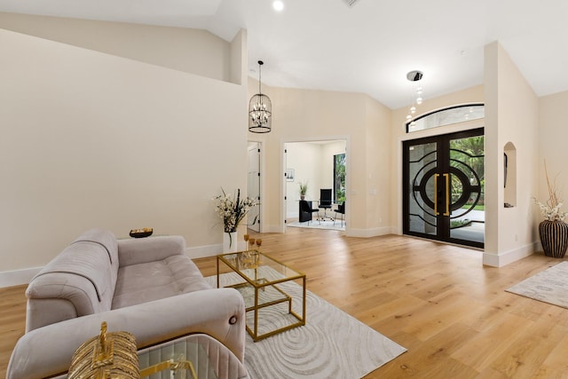 living room with an inviting chandelier, high vaulted ceiling, and light hardwood / wood-style floors