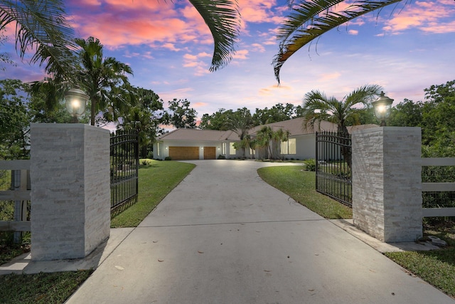 view of front of property with a lawn, a gate, a fenced front yard, concrete driveway, and a garage