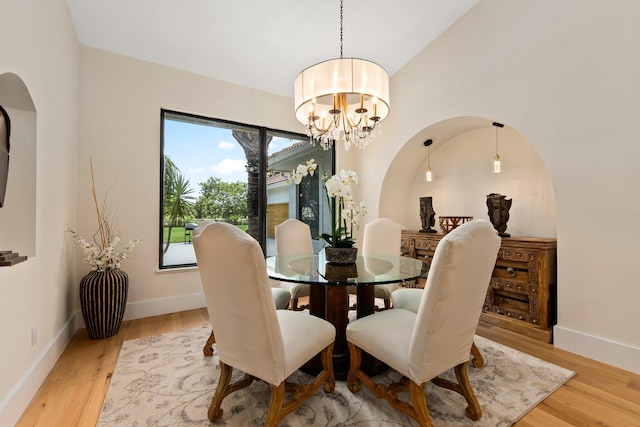 dining room featuring light hardwood / wood-style flooring, lofted ceiling, and a notable chandelier