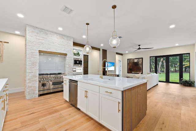 kitchen featuring white cabinetry, ceiling fan, a center island with sink, appliances with stainless steel finishes, and light hardwood / wood-style flooring