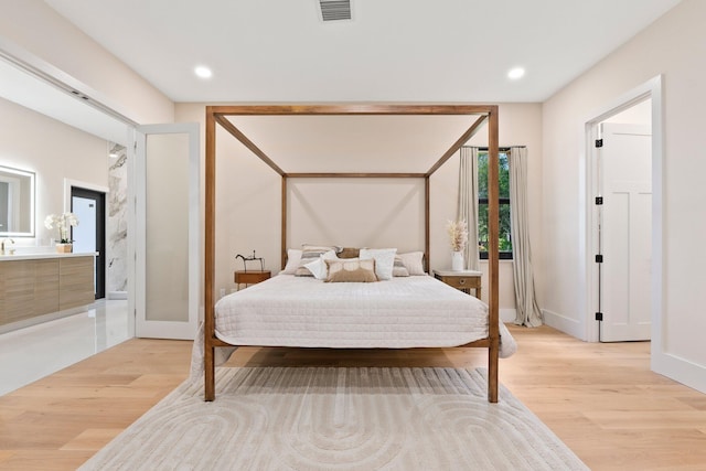 bedroom featuring ensuite bathroom and light wood-type flooring