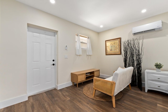 sitting room with a wall mounted AC and dark wood-type flooring