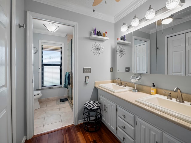 bathroom featuring toilet, ceiling fan, wood-type flooring, ornamental molding, and double sink vanity