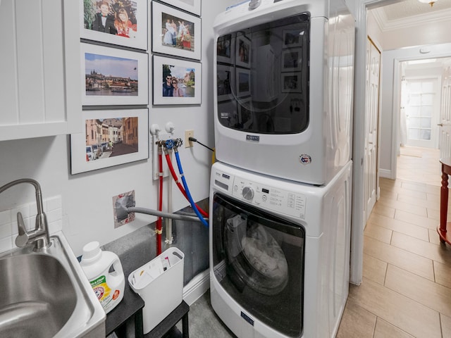 laundry area featuring ornamental molding, sink, light tile patterned floors, and stacked washer / drying machine