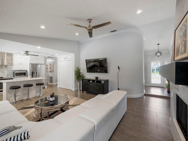 tiled living room featuring a textured ceiling, a fireplace, ceiling fan, and vaulted ceiling